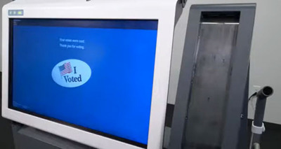 White ExpressVote XL voting machine with blue screen showing animated "I Voted" sticker with an American flag