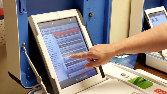 Voter presses screen on ballot marking device