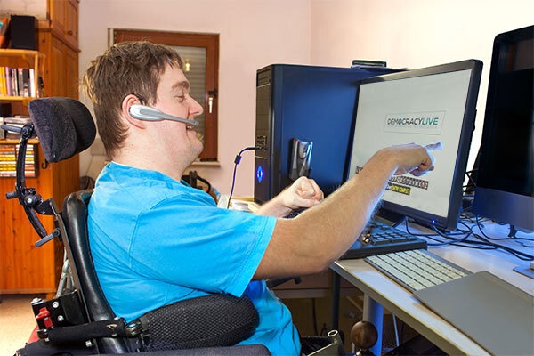 Individual in wheelchair uses remote ballot marking system on computer at a desk